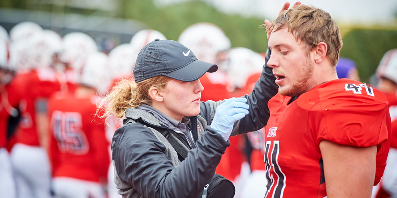 Athletic trainer assisting football player