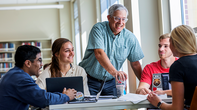 A professor chats with students in the DeWitt Library