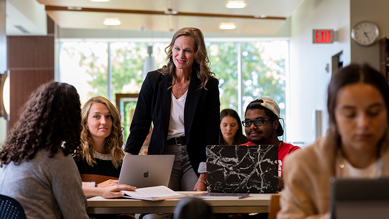 Professor works with students in a study hall