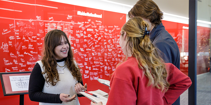 An admissions counselor greeting two student visitors