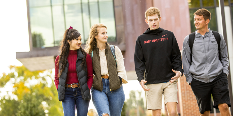 Four students walking by the science building