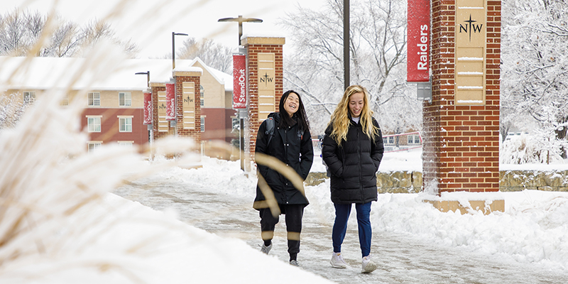 Two students walking across a snowy campus