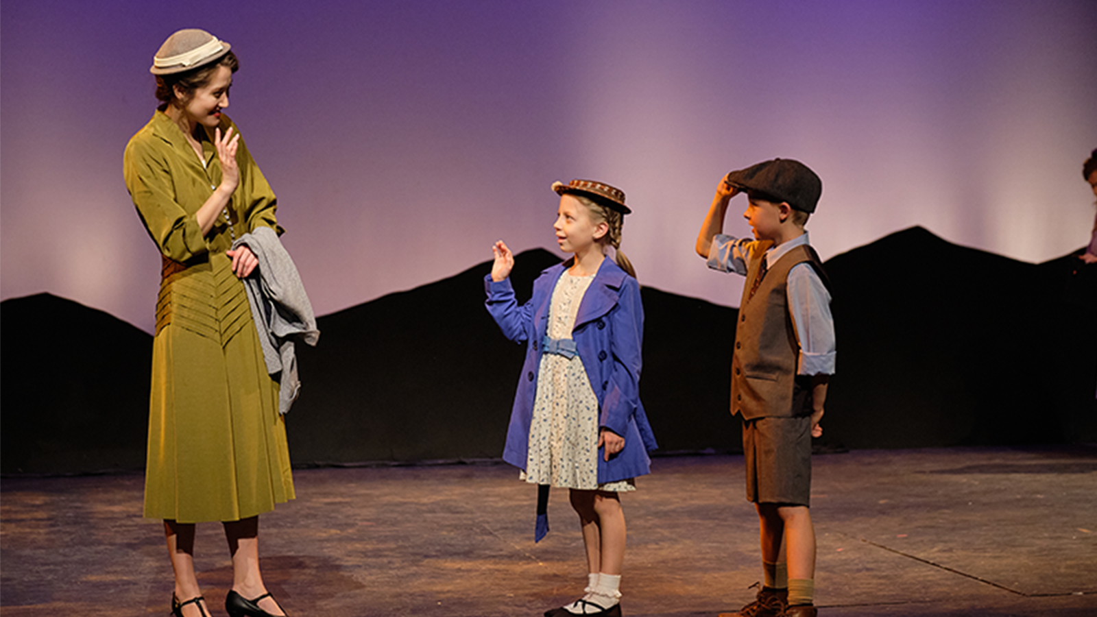 A woman on stage with two children