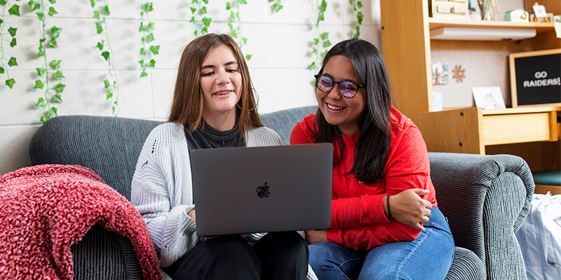 Two female students study together in a dorm room