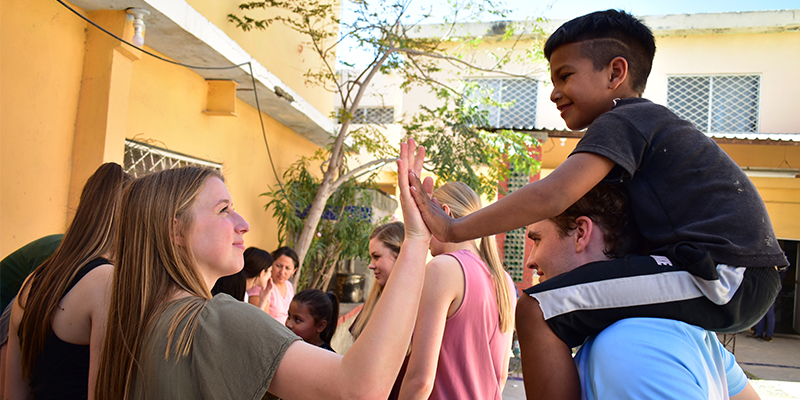 A young woman offers a high five to a child