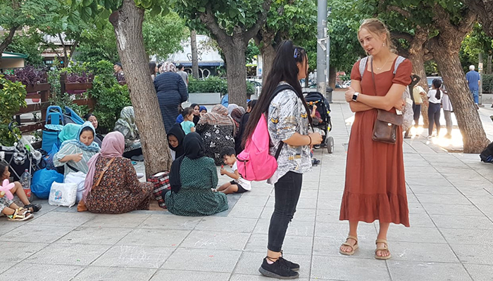 Two young women engaged in conversation on the streets of Greece