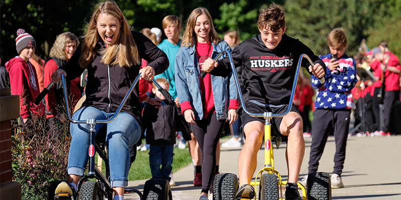 Two kids ride trikes at Morning on the Green at the 2019 Raider Nation Celebration