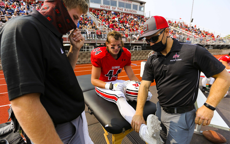 Athletic trainers assisting football player