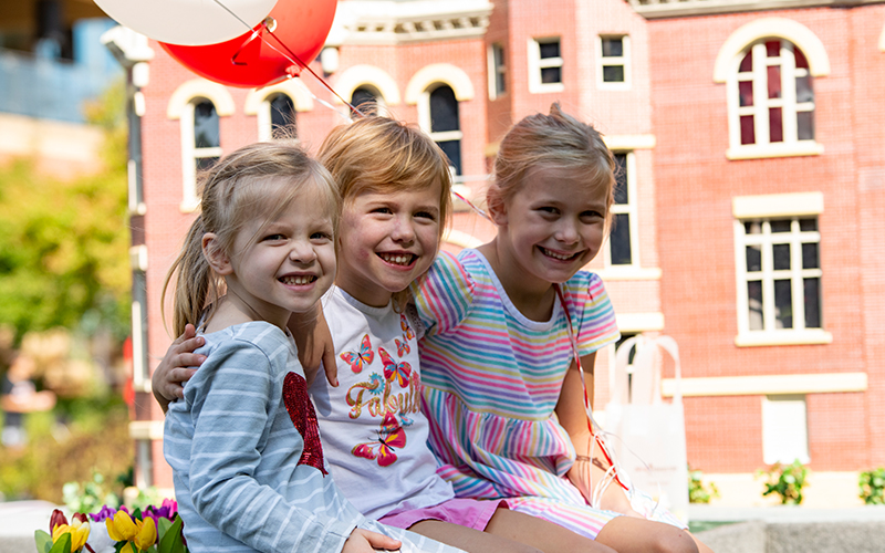 Three girls sit on a Zwemer Hall float at Morning on the Green